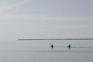 Two kayaks in a wide, flat ocean