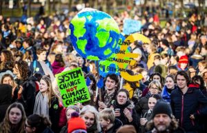 A large crowd of students holding various signs. One reads "system change not climate change".