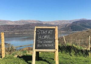 COVID sign urging people to stay home in front of Welsh Estuary