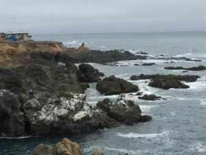 Rocky ocean scene with small fishers visible on rocks